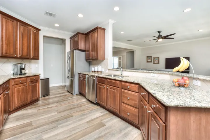 Kitchen with visible vents, light wood finished floors, ceiling fan, stainless steel appliances, and a sink