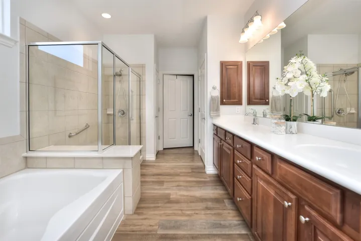 Full bathroom featuring a sink, a shower stall, wood finished floors, a bath, and double vanity