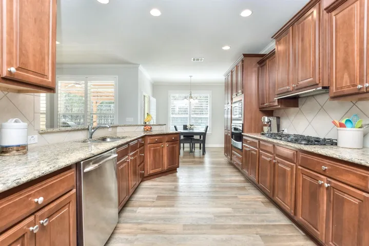 Kitchen with visible vents, light wood-style flooring, crown molding, appliances with stainless steel finishes, and a sink