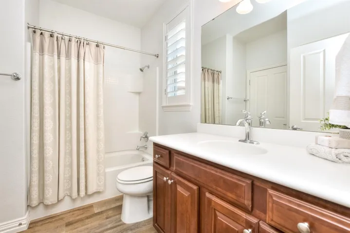 Bathroom featuring shower / bath combo with shower curtain, vanity, toilet, and wood finished floors