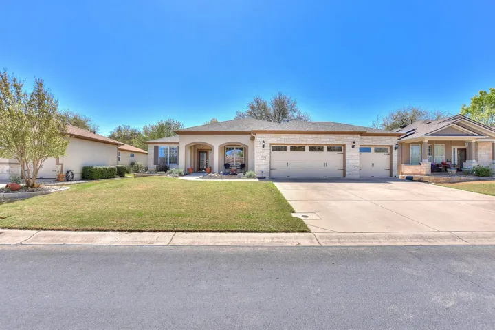 Ranch-style house featuring concrete driveway, stone siding, a front lawn, covered porch, and a garage