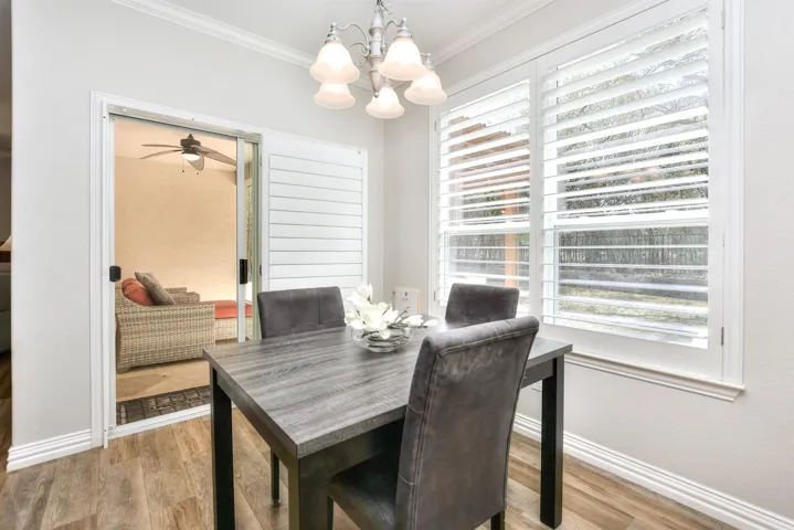 Dining area featuring baseboards, wood finished floors, crown molding, and ceiling fan with notable chandelier