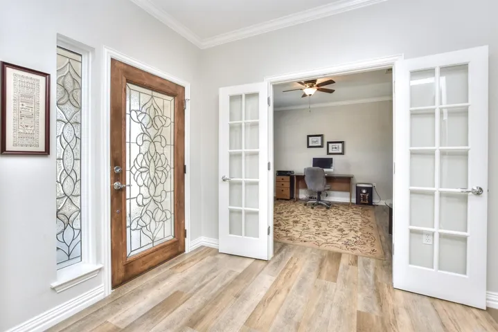 Foyer with light wood finished floors, baseboards, ornamental molding, and french doors
