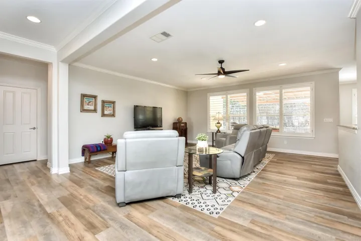 Living area featuring wood finished floors, crown molding, and ceiling fan