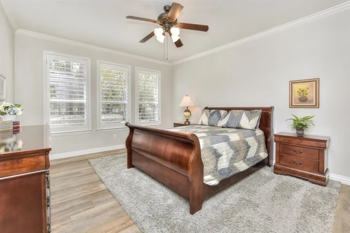Bedroom with baseboards, ceiling fan, wood finished floors, and crown molding