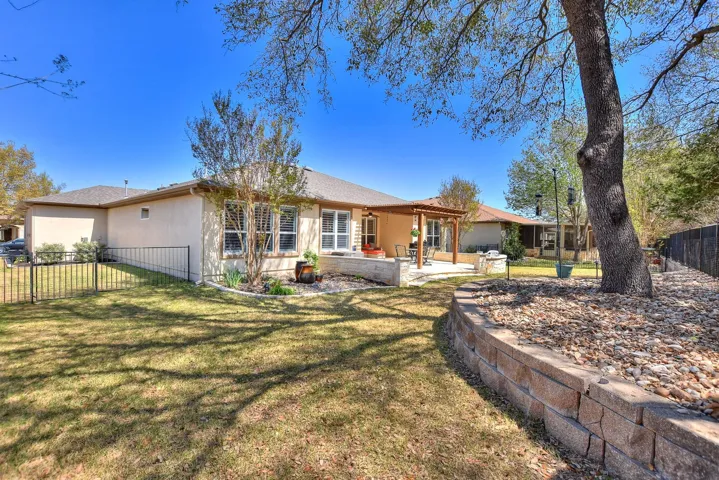 Rear view of property with a lawn, stucco siding, fence, and a patio