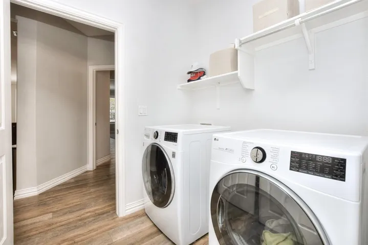 Laundry area featuring baseboards, laundry area, light wood-style floors, and washer and clothes dryer