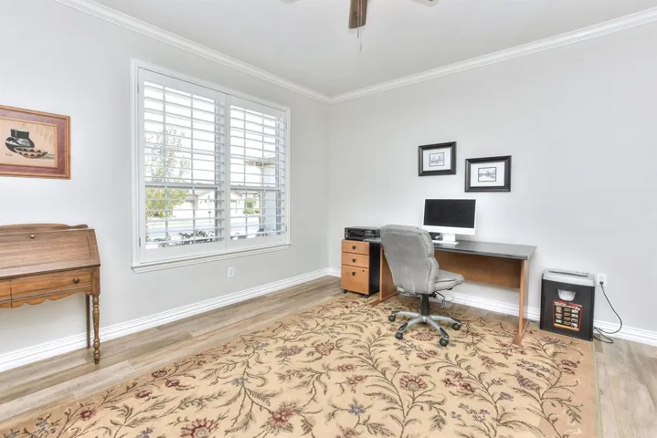 Office area featuring baseboards, ceiling fan, wood finished floors, and crown molding