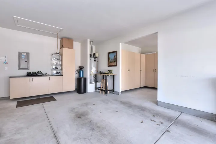 Garage featuring electric panel and gas water heater