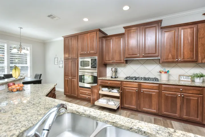 Kitchen with visible vents, crown molding, wood finished floors, stainless steel appliances, and backsplash