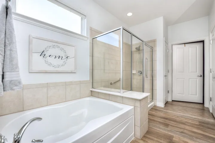 Bathroom featuring wood finished floors, a garden tub, and a shower stall