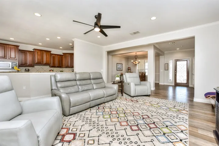 Living room featuring visible vents, recessed lighting, light wood-type flooring, and ceiling fan with notable chandelier