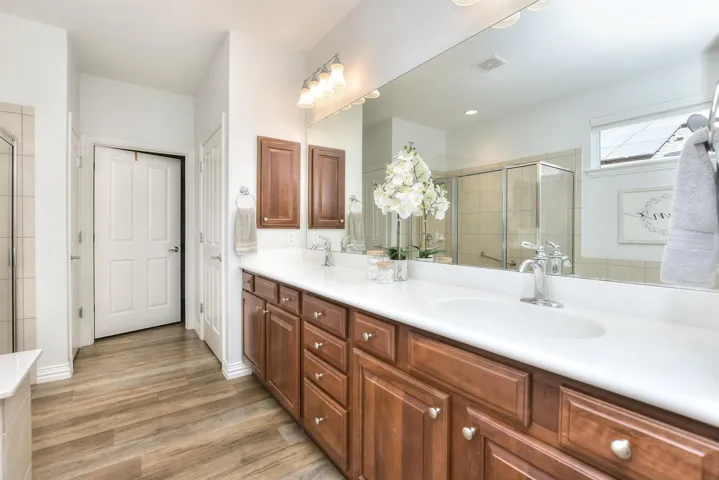 Full bathroom with a stall shower, double vanity, wood finished floors, and a sink