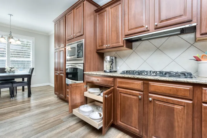 Kitchen with tasteful backsplash, crown molding, stainless steel appliances, under cabinet range hood, and a chandelier