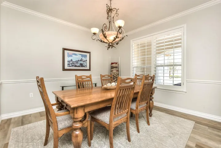 Dining area featuring a notable chandelier, crown molding, baseboards, and wood finished floors