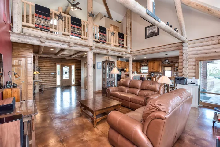 Tiled living room with high vaulted ceiling, beam ceiling, and a ceiling fan