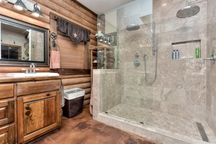Bathroom with a shower stall, rustic walls, and vanity