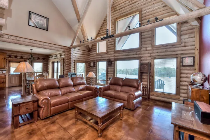 Living area with high vaulted ceiling, tile patterned flooring, and beam ceiling