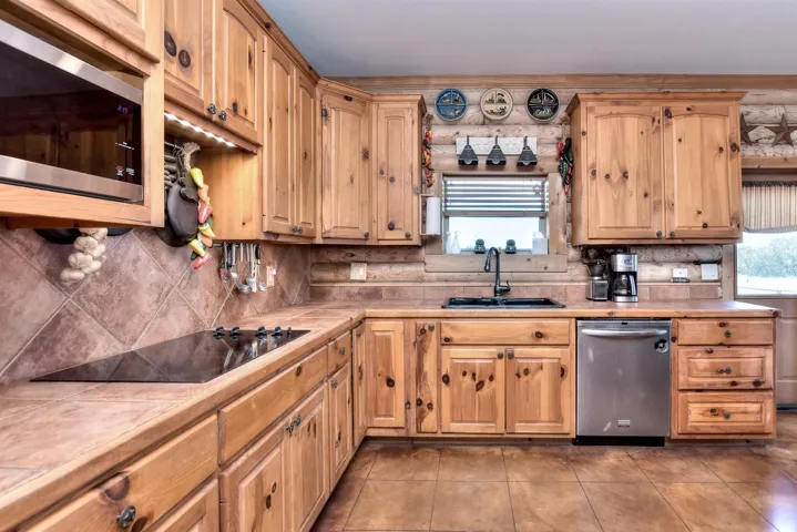 Kitchen with decorative backsplash, a sink, tile counters, and appliances with stainless steel finishes