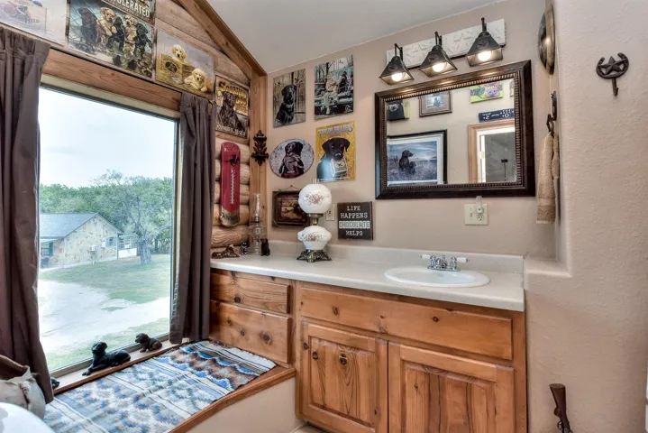 Bathroom with vanity, a textured wall, and lofted ceiling
