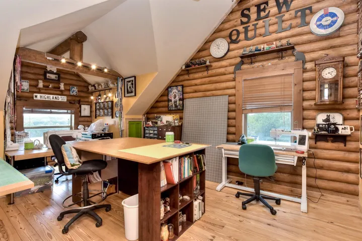 Office space featuring hardwood / wood-style floors, log walls, and high vaulted ceiling