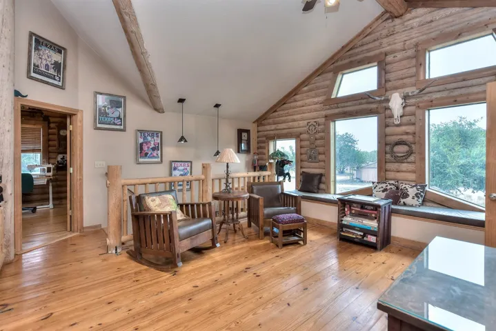 Living room with hardwood / wood-style flooring, high vaulted ceiling, beamed ceiling, and ceiling fan