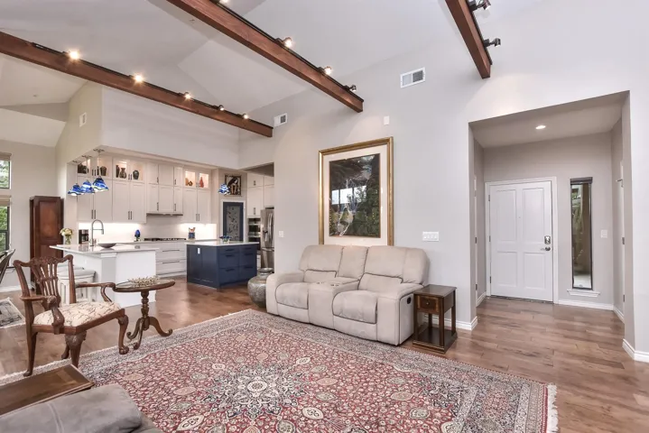 Living room featuring wood-style flooring, beam ceiling, and high ceilings