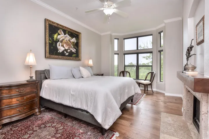 Bedroom featuring crown molding, a high-end fireplace, and hardwood / wood-style floors