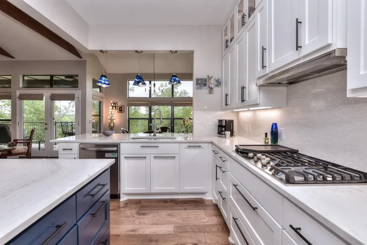 Kitchen with blue cabinets, stainless steel gas cooktop, dishwasher, and white cabinetry