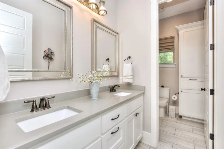 Bathroom featuring toilet, double vanity, and baseboards