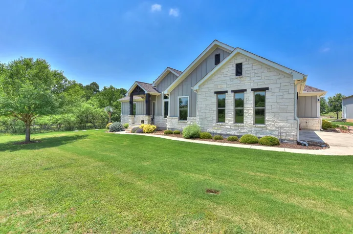 Craftsman inspired home featuring board and batten siding, a front yard, and stone siding