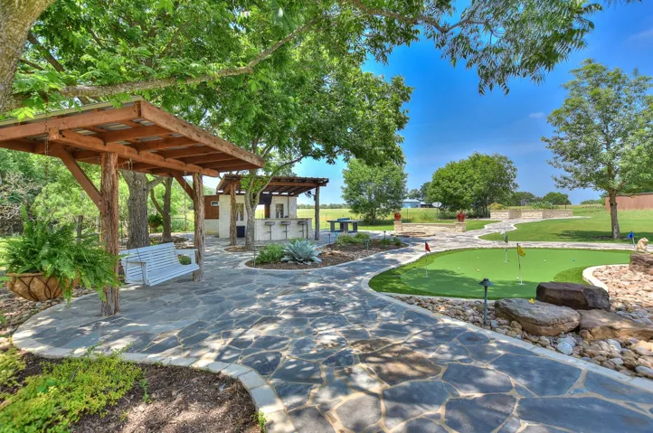 Surrounding community with a putting area, a patio area, and a pergola