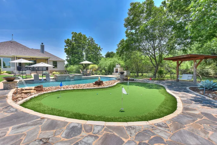 View of property's community featuring a putting area, a patio area, and a pool