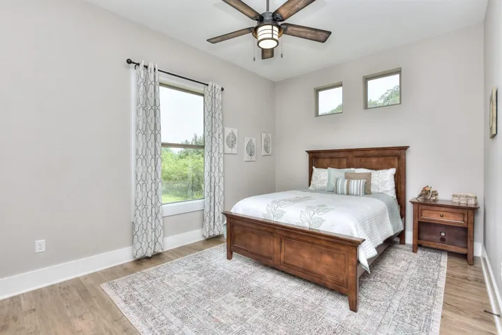 Bedroom featuring light wood-style floors, multiple windows, baseboards, and a ceiling fan