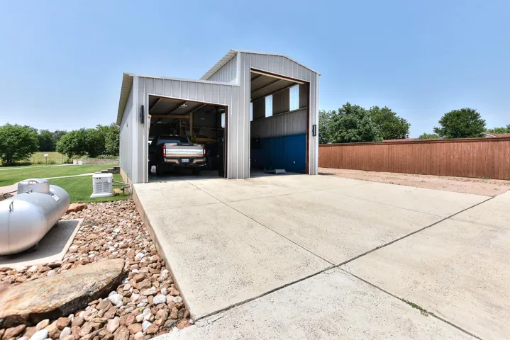 View of side of home featuring fence, an outbuilding, a garage, and a pole building