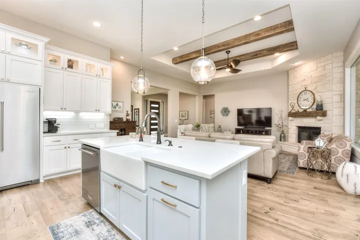 Kitchen with appliances with stainless steel finishes, a sink, light countertops, light wood-style floors, and pendant lighting
