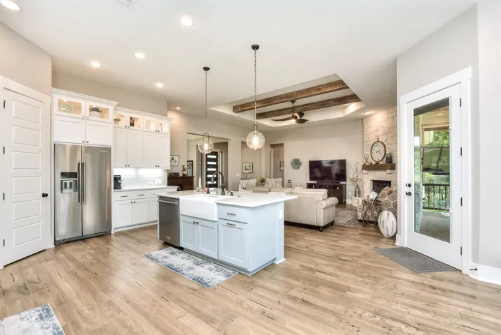 Kitchen with stainless steel appliances, a raised ceiling, open floor plan, light wood-style floors, and white cabinets