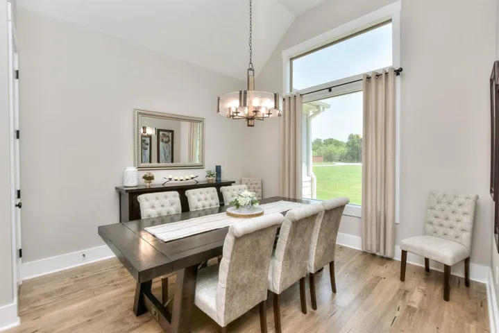 Dining space featuring a chandelier, vaulted ceiling, light wood-style flooring, and baseboards