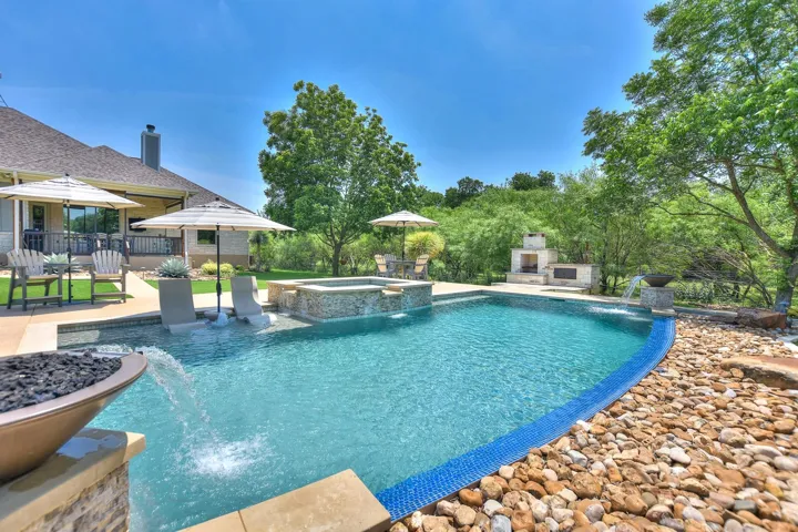 View of pool with a patio, a stone fireplace, and a pool with connected hot tub