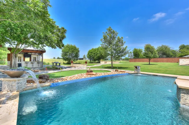 Swimming pool featuring a putting area and a yard