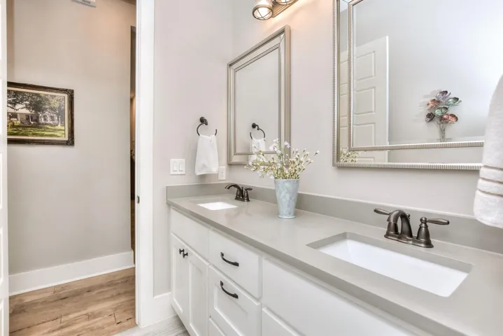 Bathroom with wood finished floors, double vanity, and baseboards