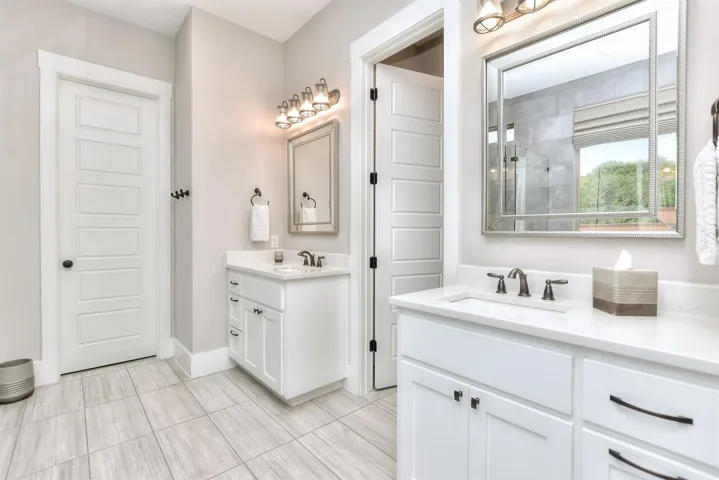 Full bathroom with two vanities, a tile shower, and tile patterned floors