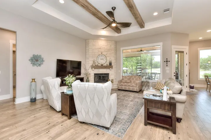 Living area with a ceiling fan, light wood finished floors, a fireplace, baseboards, and recessed lighting