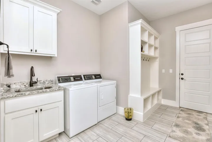 Washroom with washing machine and dryer, cabinet space, and baseboards