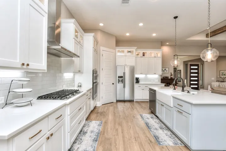 Kitchen featuring appliances with stainless steel finishes, a sink, wall chimney exhaust hood, white cabinets, and recessed lighting