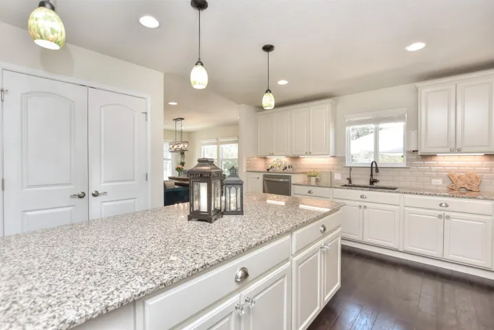 Kitchen featuring a sink, dishwasher, white cabinetry, dark wood-type flooring, and recessed lighting