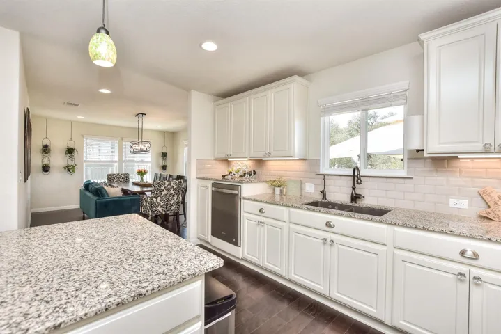 Kitchen with a sink, dishwasher, white cabinets, tasteful backsplash, and recessed lighting