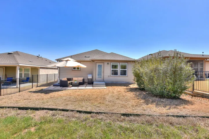 Back of house with an outdoor living space, a fenced backyard, and a patio area