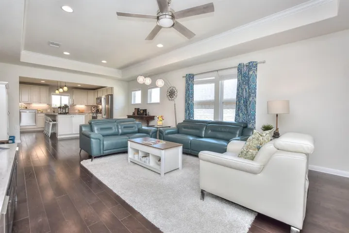 Living room featuring a tray ceiling, dark wood finished floors, crown molding, ceiling fan, and recessed lighting