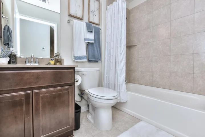 Bathroom with toilet, tile patterned floors, vanity, shower / bath combination with curtain, and baseboards
